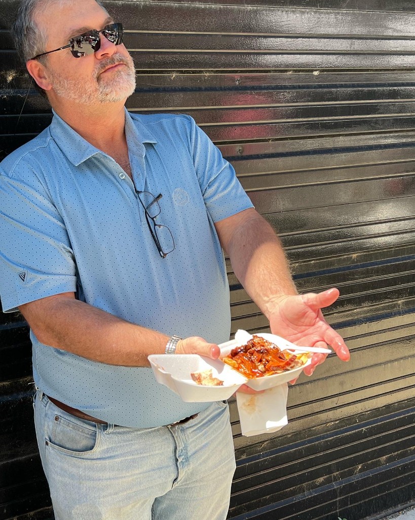 Guest with loaded fries and festival meal in a takeout tray