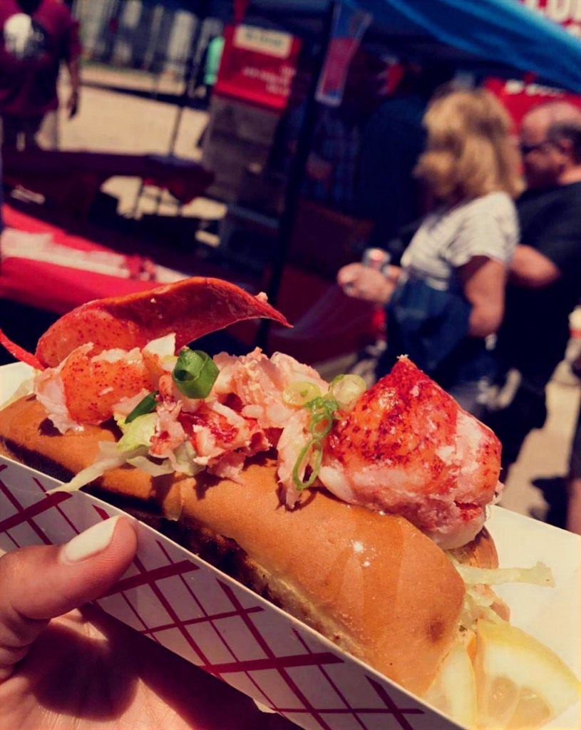 Two women walking past the Haute Sausage food truck with trays at Chicago Food Truck Festival