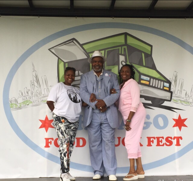 Hands holding a loaded New England-style lobster roll in a paper tray at the street festival