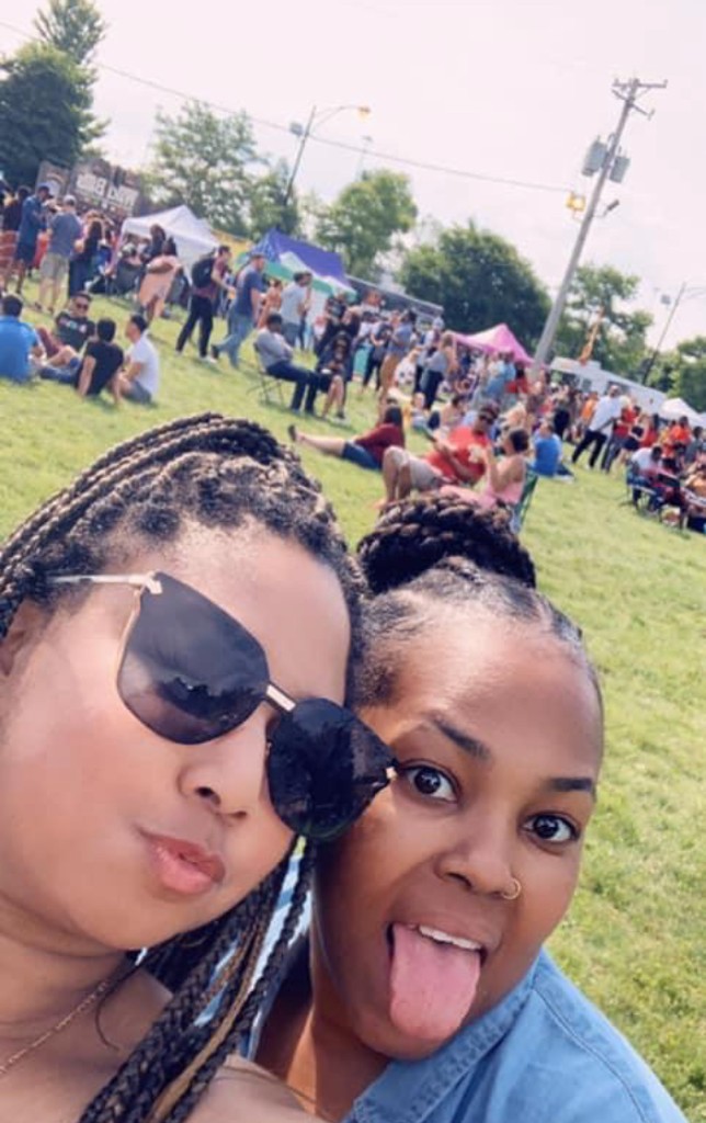 Lobster roll with crispy bacon held outdoors with another roll on the grass behind