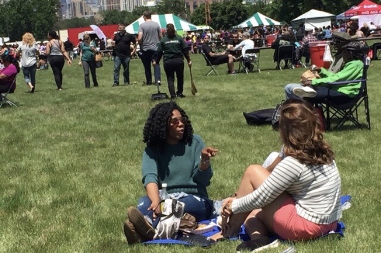 Sunny plaza with food trucks and families browsing vendor stalls at the festival
