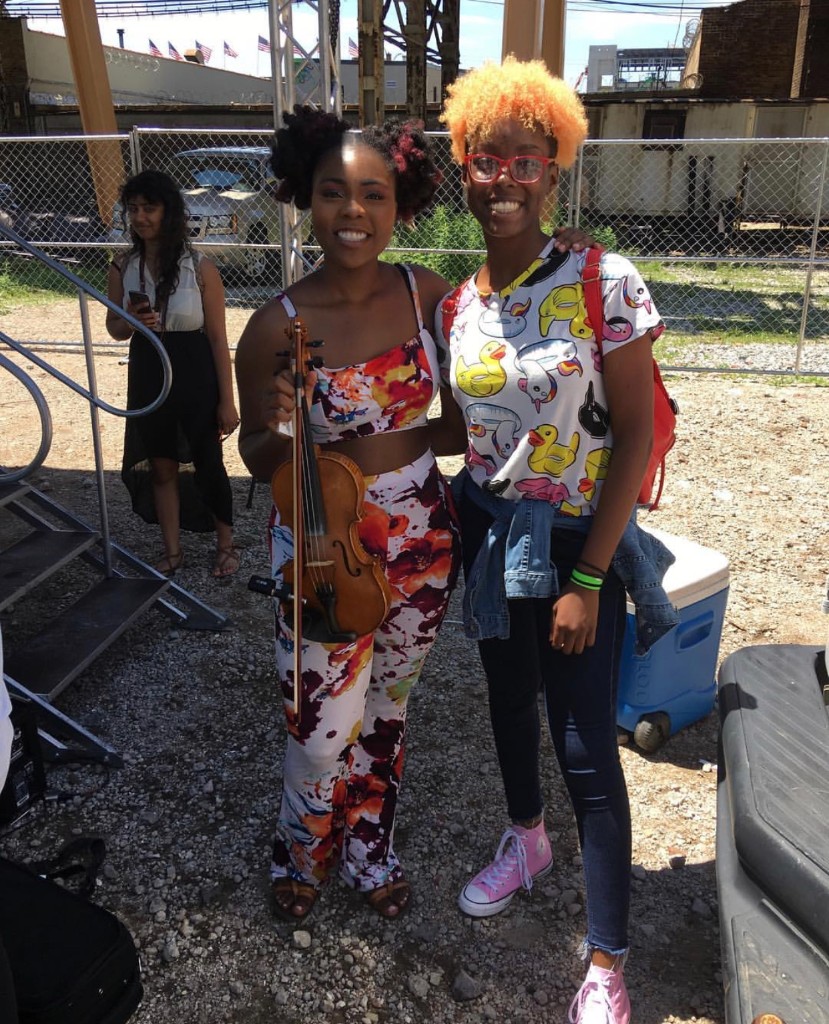 Two friends posing together with a violin at the summer festival