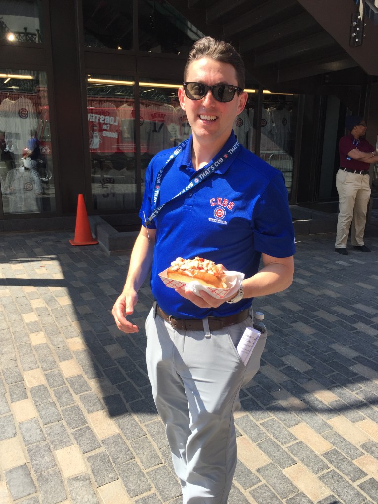Guest in Cubs gear with a lobster roll outside Wrigley Field
