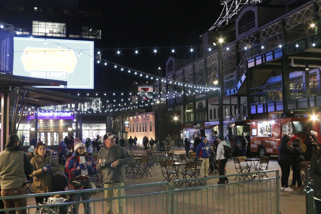Picnic table with Bud Light banner near food truck row and stroller on the lawn at night