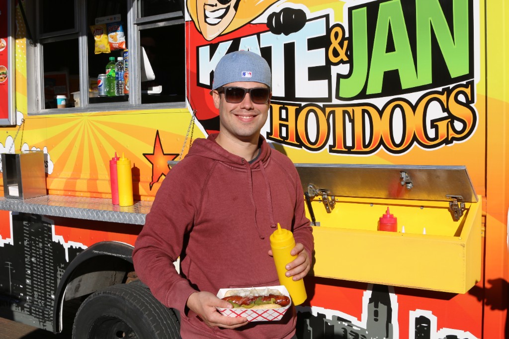 Guest with a hot dog in front of the Kate & Jan Hotdogs truck at Wrigley Field