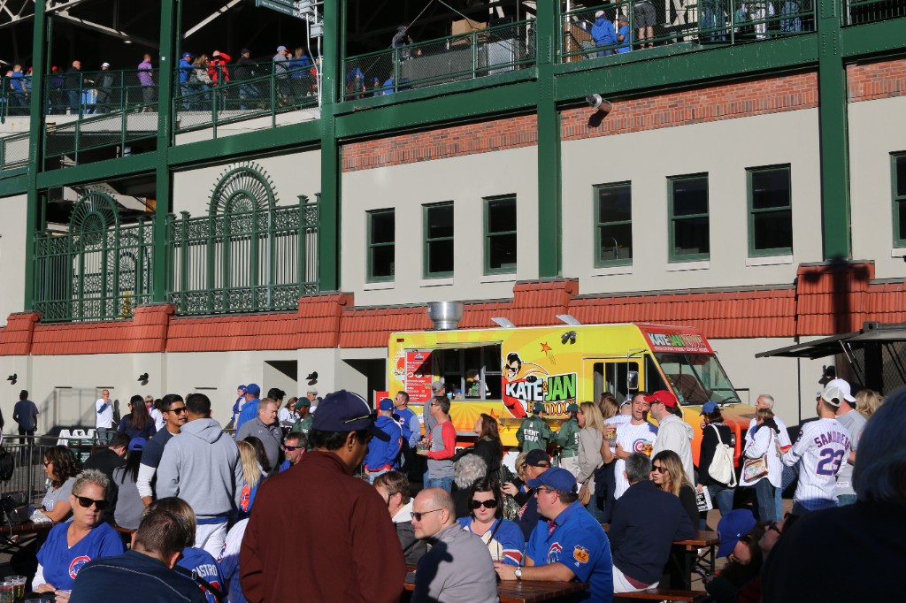 Fans and picnic tables near the Kate & Jan Hotdogs truck outside Wrigley Field