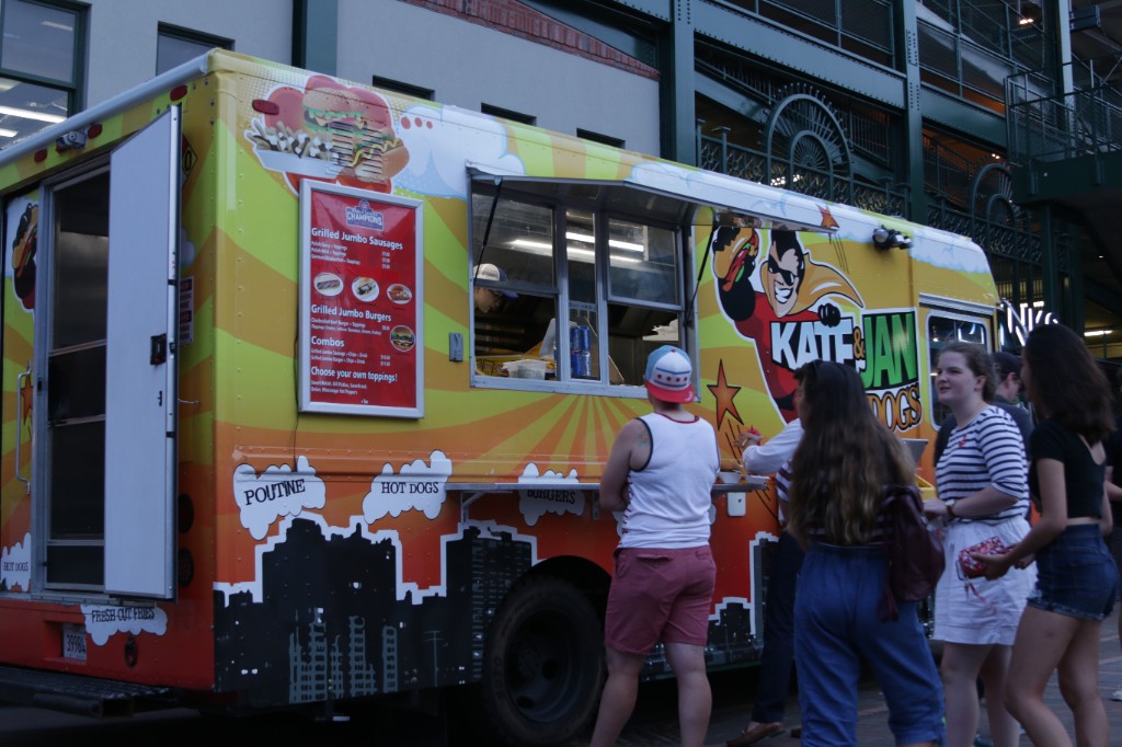 People in lawn chairs watching the outdoor movie screen beside Wrigley Field at dusk