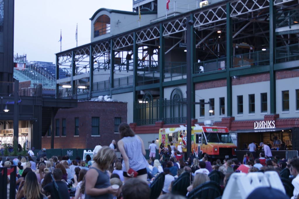 Outdoor screening at The Park at Wrigley with stadium structure and scoreboard visible at dusk