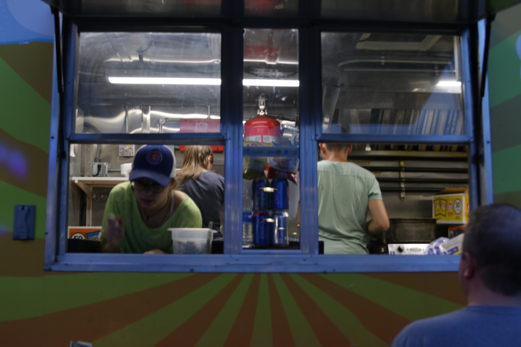 Food truck crew working the service window under bright lights during a Wrigley Field event