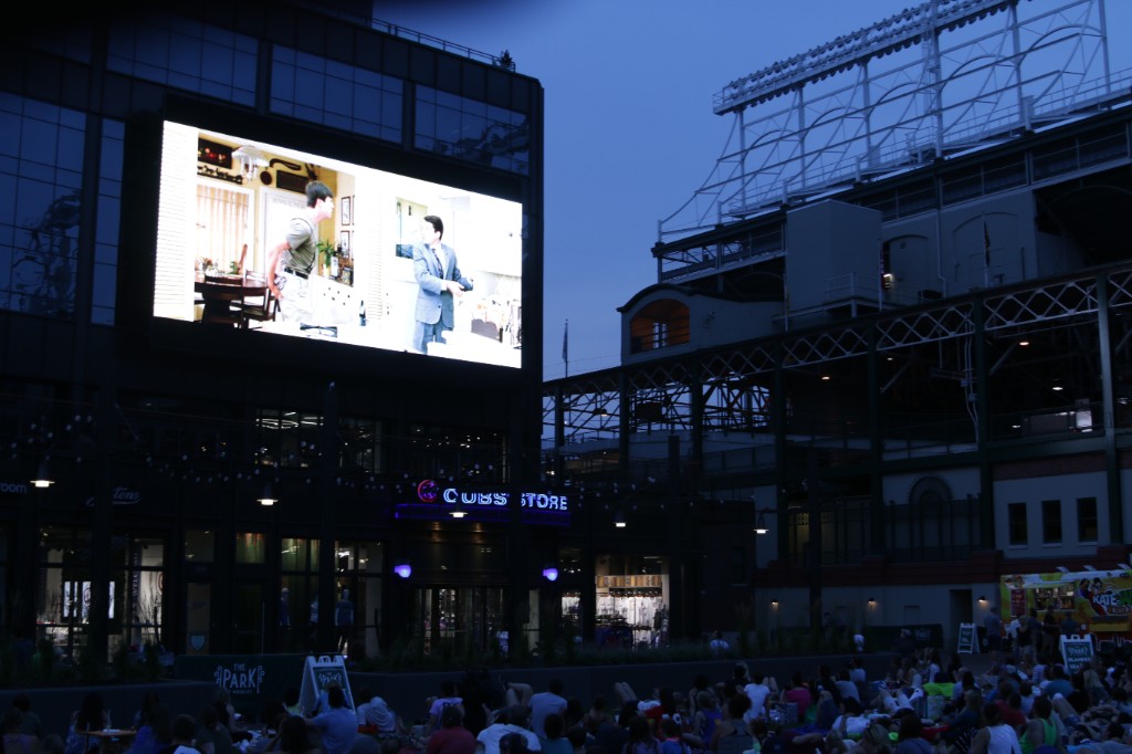Classic comedy on the outdoor screen with fans gathered on chairs at The Park at Wrigley