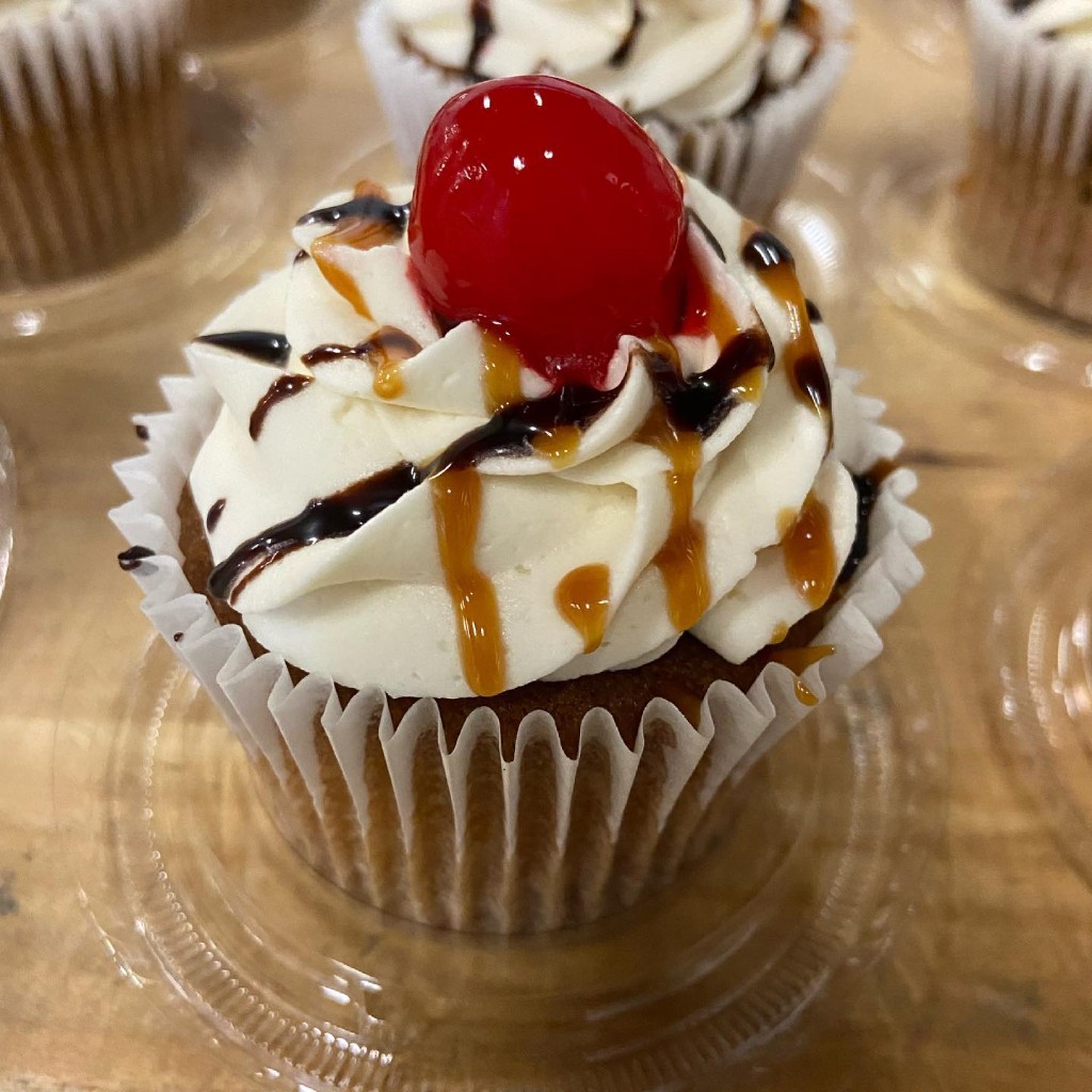 Ms. Tittle's Cupcakes — vanilla cupcake topped with swirled buttercream, chocolate and caramel drizzle, and a maraschino cherry